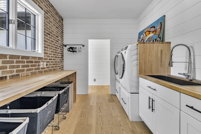 kitchen with butcher block countertops, sink, light hardwood / wood-style flooring, independent washer and dryer, and white cabinets