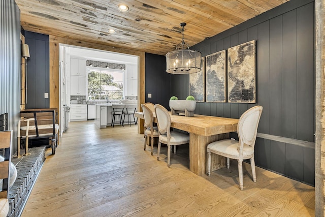 dining area with sink, wood ceiling, light hardwood / wood-style flooring, a notable chandelier, and wood walls