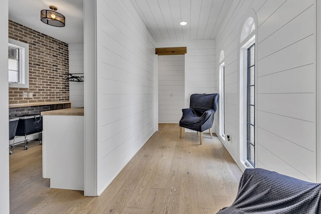 hall featuring brick wall and light wood-type flooring