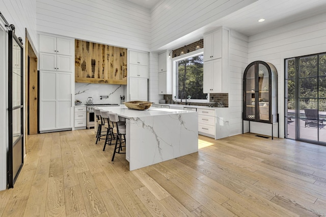 kitchen with white cabinetry, light stone countertops, a center island, and a barn door