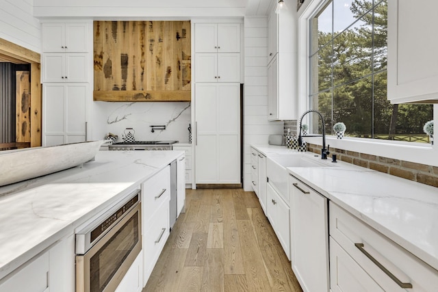 kitchen featuring stainless steel microwave, light stone countertops, and white cabinets