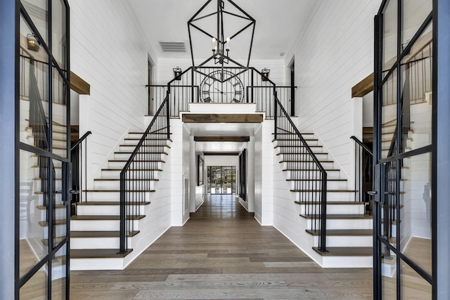 foyer with crown molding, a towering ceiling, a chandelier, and dark hardwood / wood-style flooring