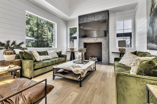 living room with a large fireplace, a healthy amount of sunlight, and light wood-type flooring