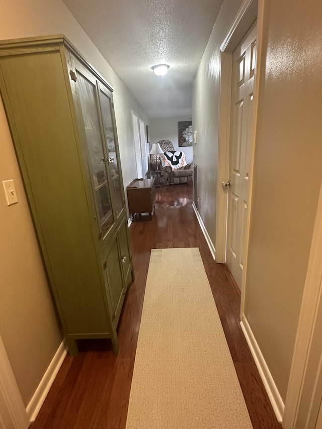 hallway with dark wood-type flooring and a textured ceiling