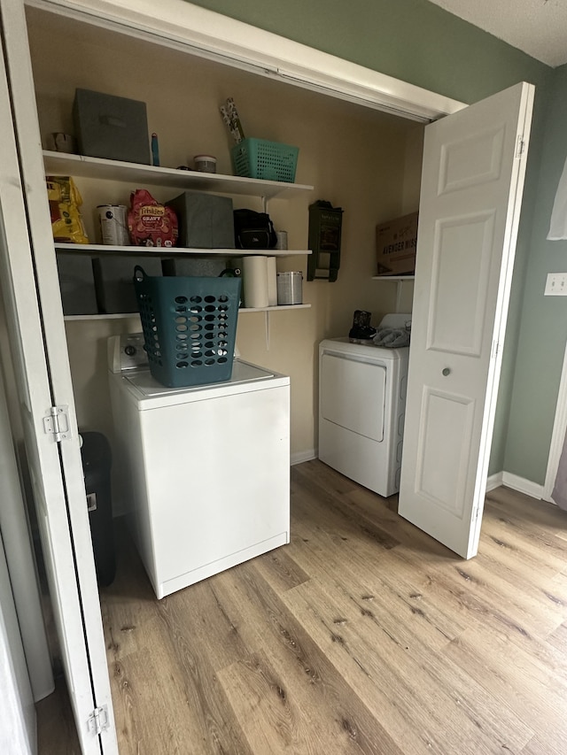 laundry room featuring washing machine and dryer and light hardwood / wood-style flooring