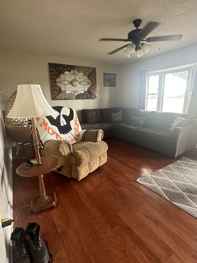 living room with dark wood-type flooring, a textured ceiling, and ceiling fan