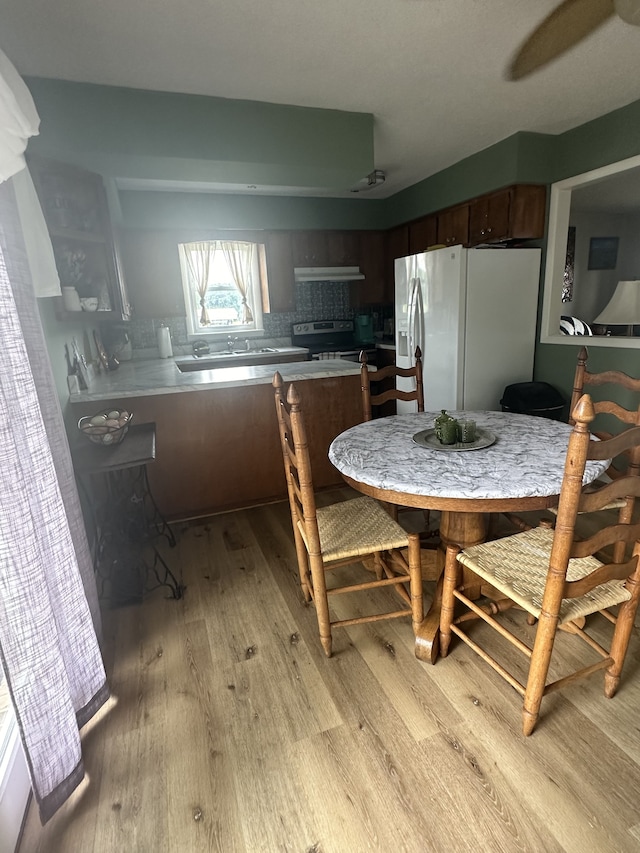 kitchen with range with electric stovetop, light hardwood / wood-style floors, white refrigerator with ice dispenser, and kitchen peninsula