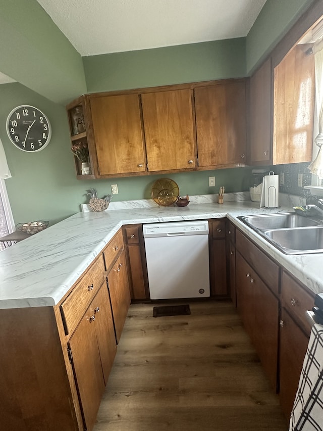 kitchen with range, kitchen peninsula, dishwasher, hardwood / wood-style floors, and sink