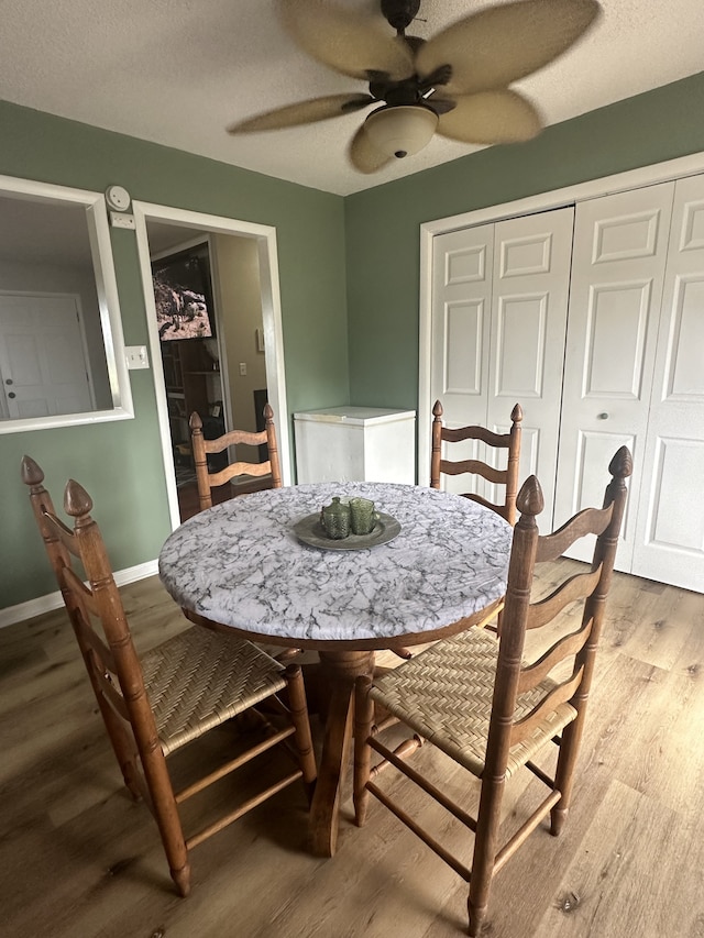 dining space featuring a textured ceiling, hardwood / wood-style floors, and ceiling fan