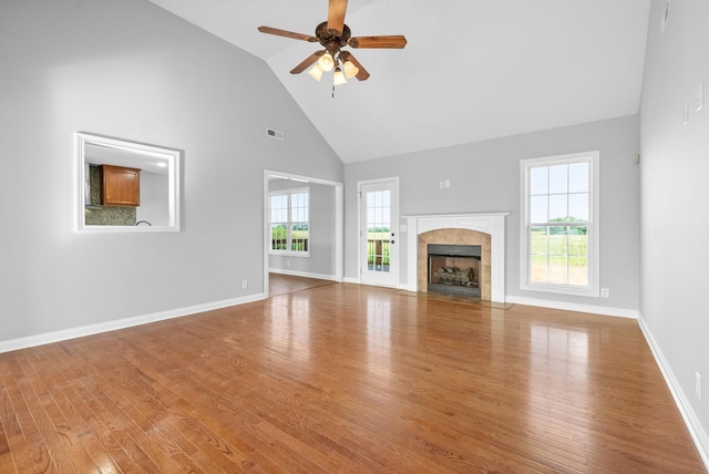 unfurnished living room featuring ceiling fan, wood-type flooring, high vaulted ceiling, and a fireplace