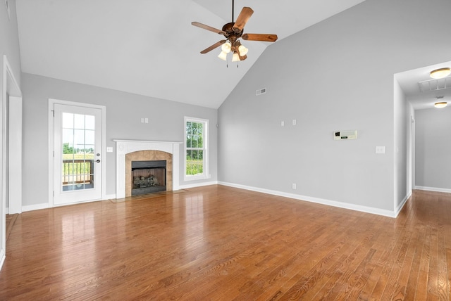 unfurnished living room featuring plenty of natural light, ceiling fan, a tiled fireplace, and hardwood / wood-style floors