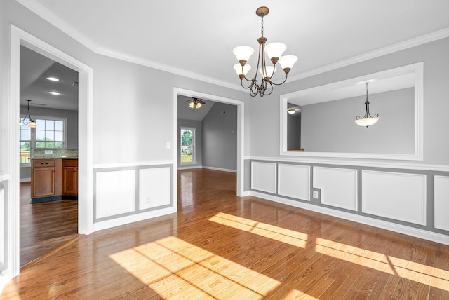 spare room with plenty of natural light, crown molding, and an inviting chandelier