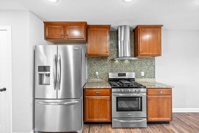 kitchen featuring decorative backsplash, wall chimney range hood, appliances with stainless steel finishes, and light wood-type flooring