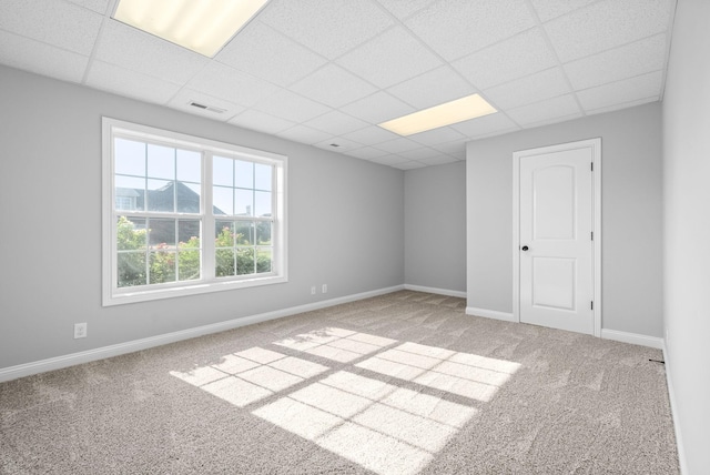 spare room featuring a paneled ceiling and light carpet