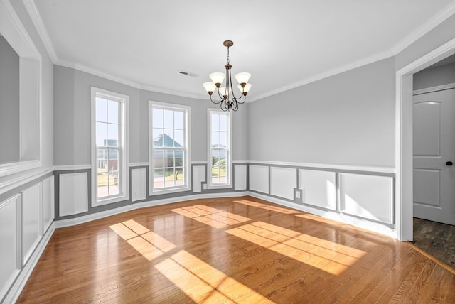 empty room featuring wood-type flooring, a notable chandelier, and crown molding