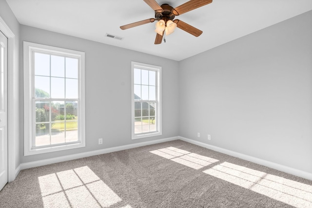 carpeted empty room with ceiling fan and a wealth of natural light