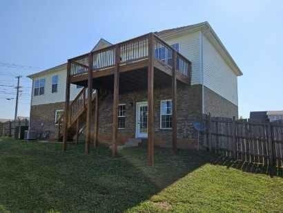 back of property featuring a lawn and a wooden deck