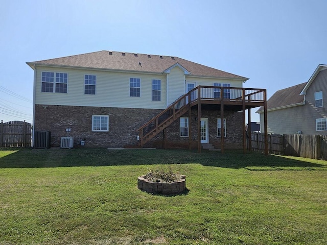 back of house featuring central AC, a wooden deck, an outdoor fire pit, and a lawn