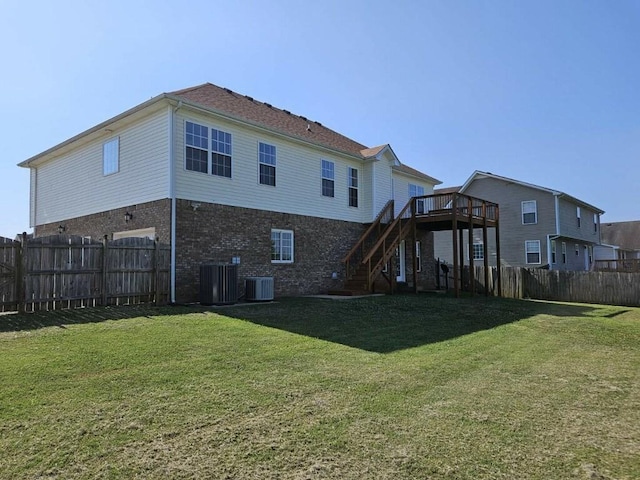 rear view of house with a deck, cooling unit, and a lawn