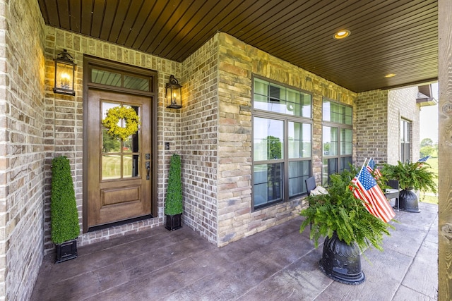 doorway to property with a porch and brick siding