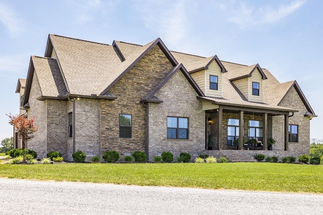 view of front of home featuring a front yard, brick siding, and roof with shingles