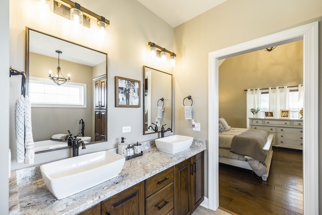 bathroom with hardwood / wood-style floors, dual bowl vanity, and a chandelier