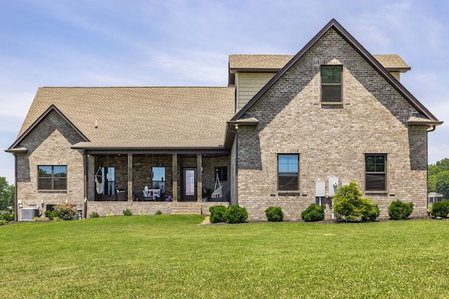 rear view of house with cooling unit and a lawn