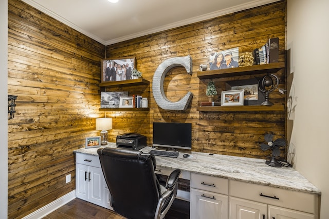 home office featuring dark hardwood / wood-style floors, wood walls, built in desk, and ornamental molding