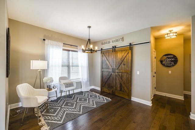 sitting room featuring an inviting chandelier, dark hardwood / wood-style flooring, and a barn door