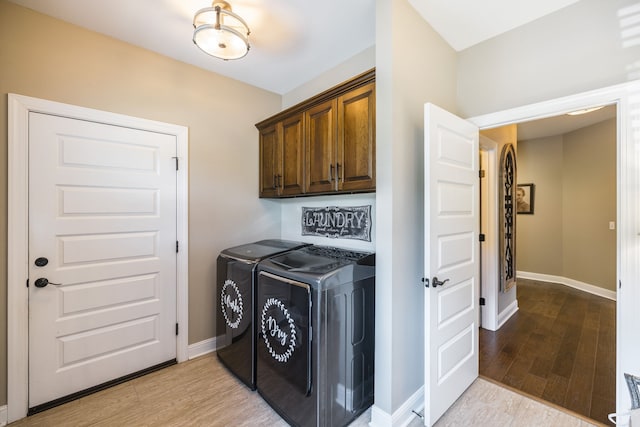 laundry area with cabinets, washer and clothes dryer, and hardwood / wood-style flooring