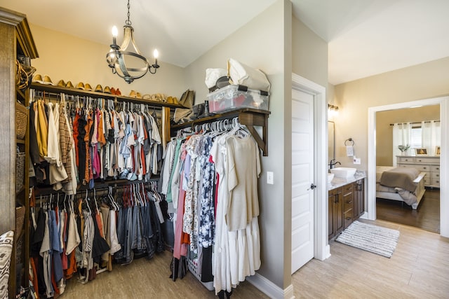 spacious closet with light hardwood / wood-style floors, sink, and an inviting chandelier