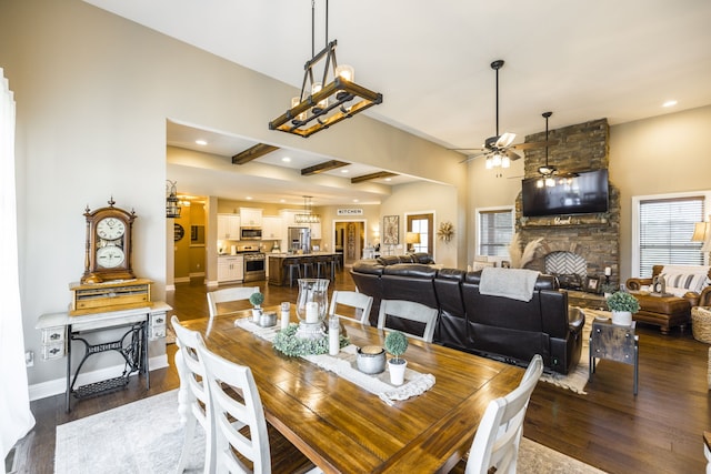 dining room featuring a stone fireplace, dark wood-type flooring, ceiling fan, and a healthy amount of sunlight