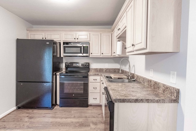 kitchen with light wood-type flooring, black appliances, and sink