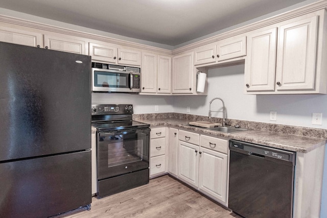 kitchen featuring cream cabinetry, light hardwood / wood-style floors, black appliances, and sink