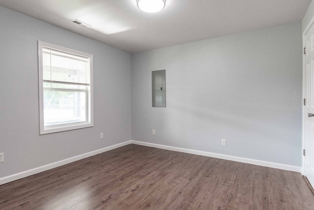 spare room featuring electric panel and dark wood-type flooring