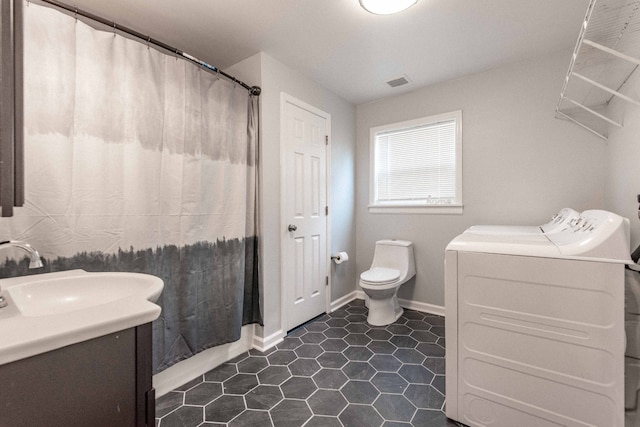 bathroom with walk in shower, washer and clothes dryer, vanity, and toilet