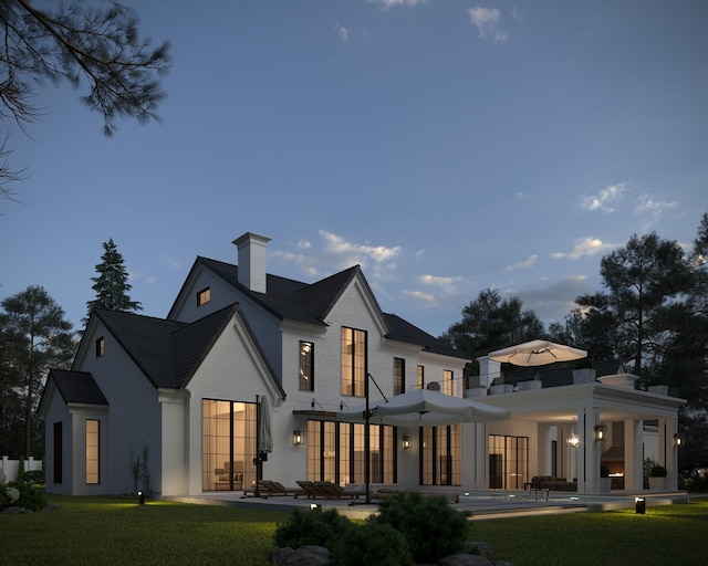 rear view of house with a patio area, a lawn, and a chimney