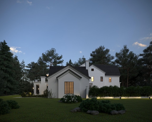 view of front facade featuring stucco siding, a chimney, and a front yard