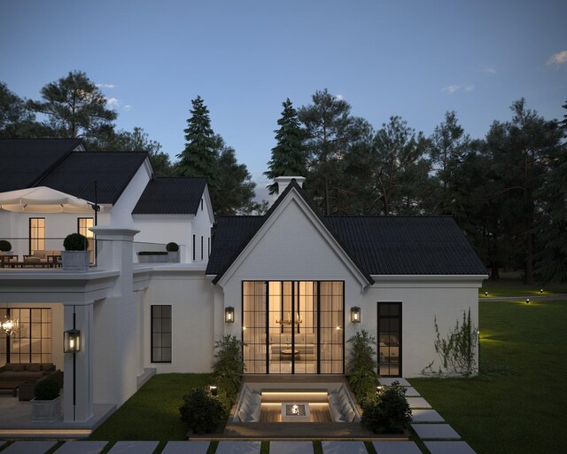 back house at dusk with a yard and a balcony