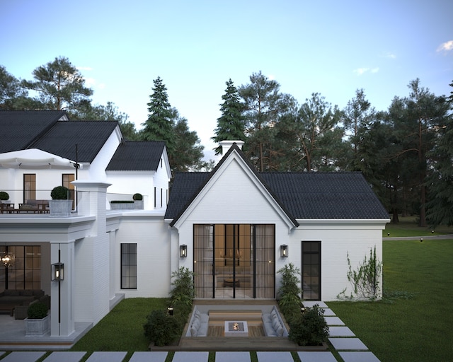 rear view of house featuring a lawn and a balcony