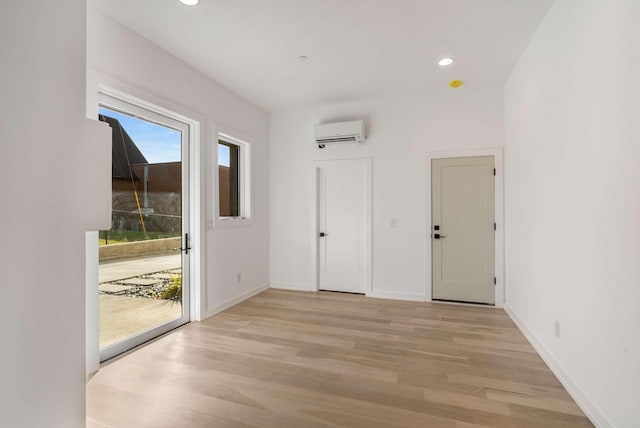 interior space with light wood finished floors, recessed lighting, a wall mounted air conditioner, and baseboards