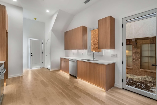 kitchen with light wood finished floors, dishwasher, light countertops, and a sink