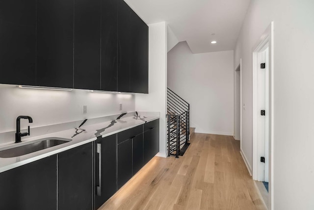 kitchen featuring light wood finished floors, a sink, light countertops, modern cabinets, and dark cabinets