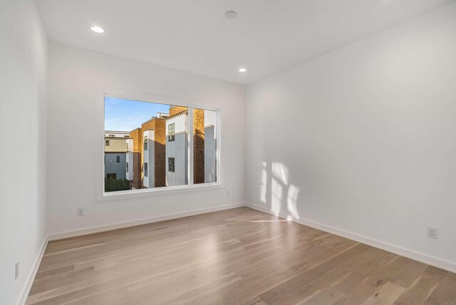 spare room with recessed lighting, baseboards, and light wood finished floors