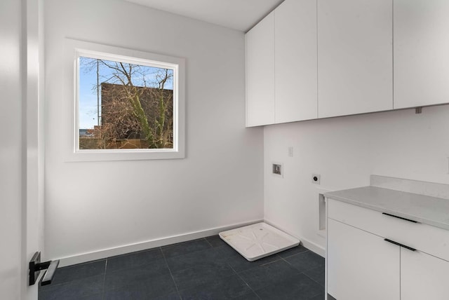 laundry area with electric dryer hookup, dark tile patterned flooring, washer hookup, cabinet space, and baseboards