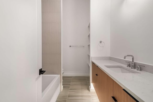 bathroom with toilet, vanity, and baseboards