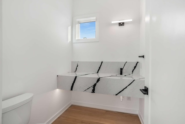 bathroom with toilet, baseboards, and wood finished floors