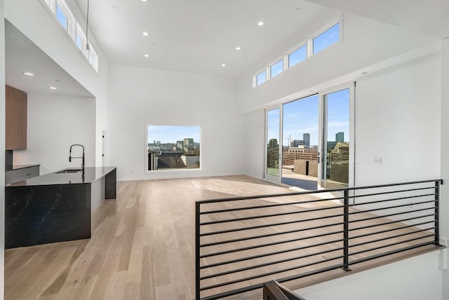 living area featuring recessed lighting, light wood-type flooring, a view of city, and a towering ceiling