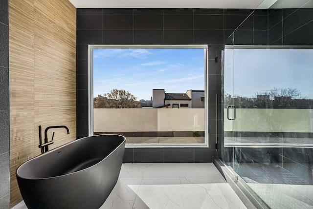 full bathroom featuring a soaking tub, marble finish floor, and a stall shower