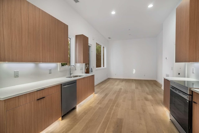 kitchen featuring light wood-type flooring, light countertops, appliances with stainless steel finishes, modern cabinets, and a sink